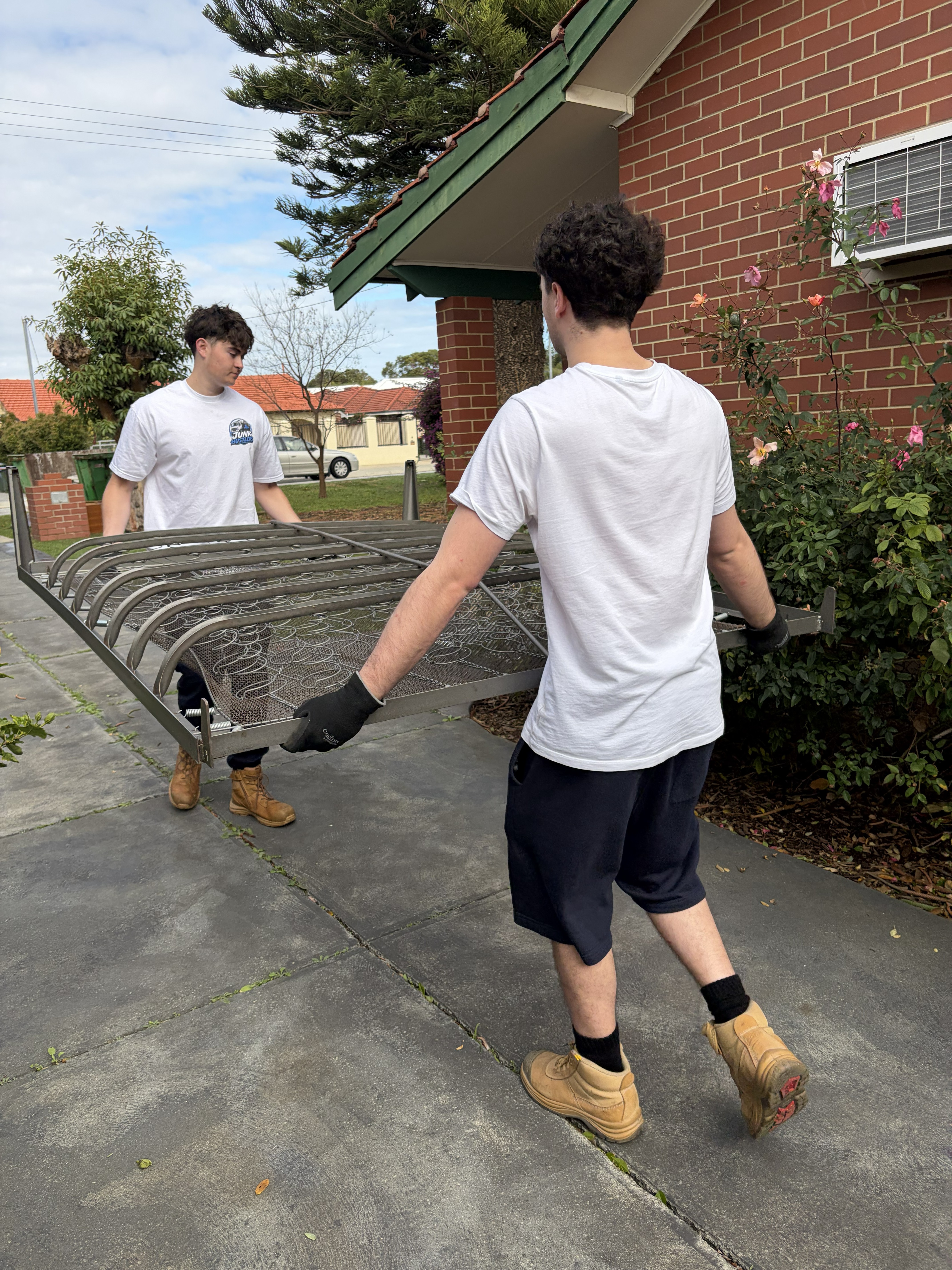 Two-person team safely carrying a bed frame during a Perth furniture move